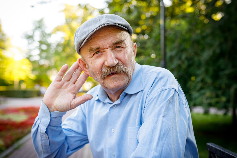 Elderly man tries to hear. An expressive gesture.
