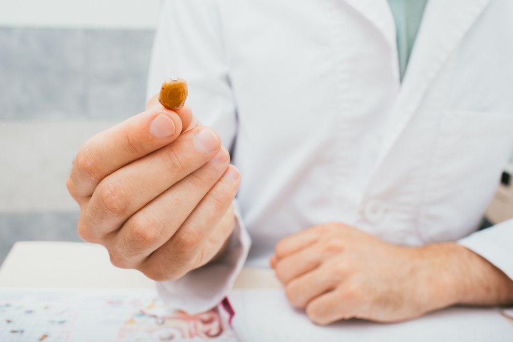 hearing specialist holding a tan colored hearing aid