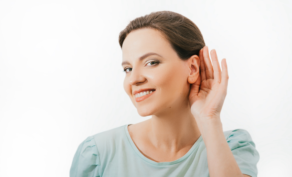 smiling woman holding hand to ear