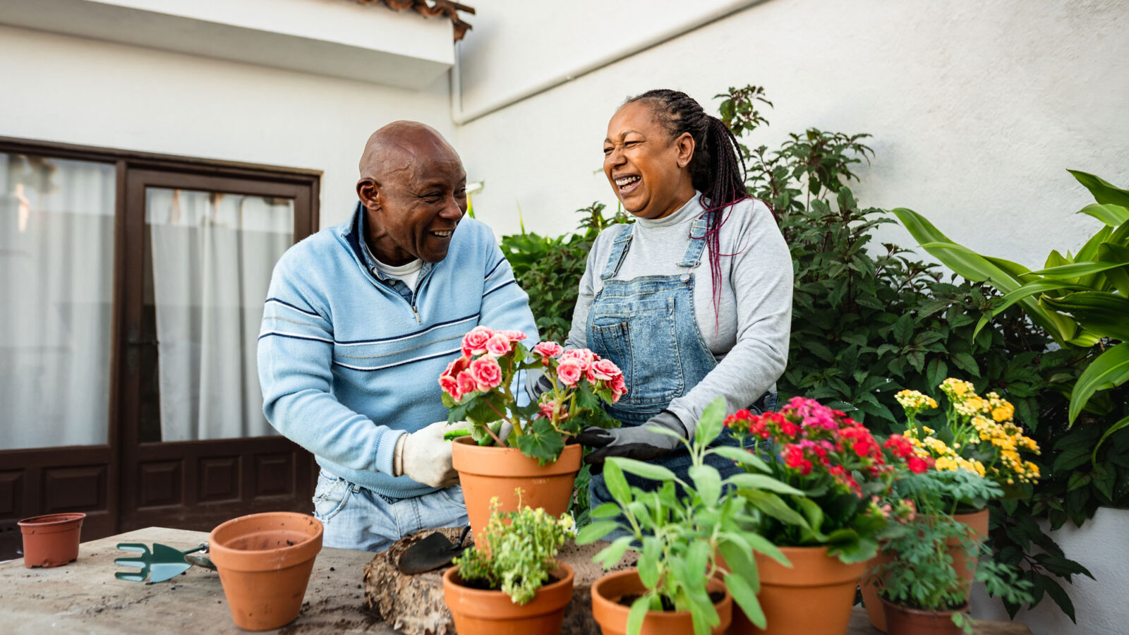 Happy African senior people gardening together at home