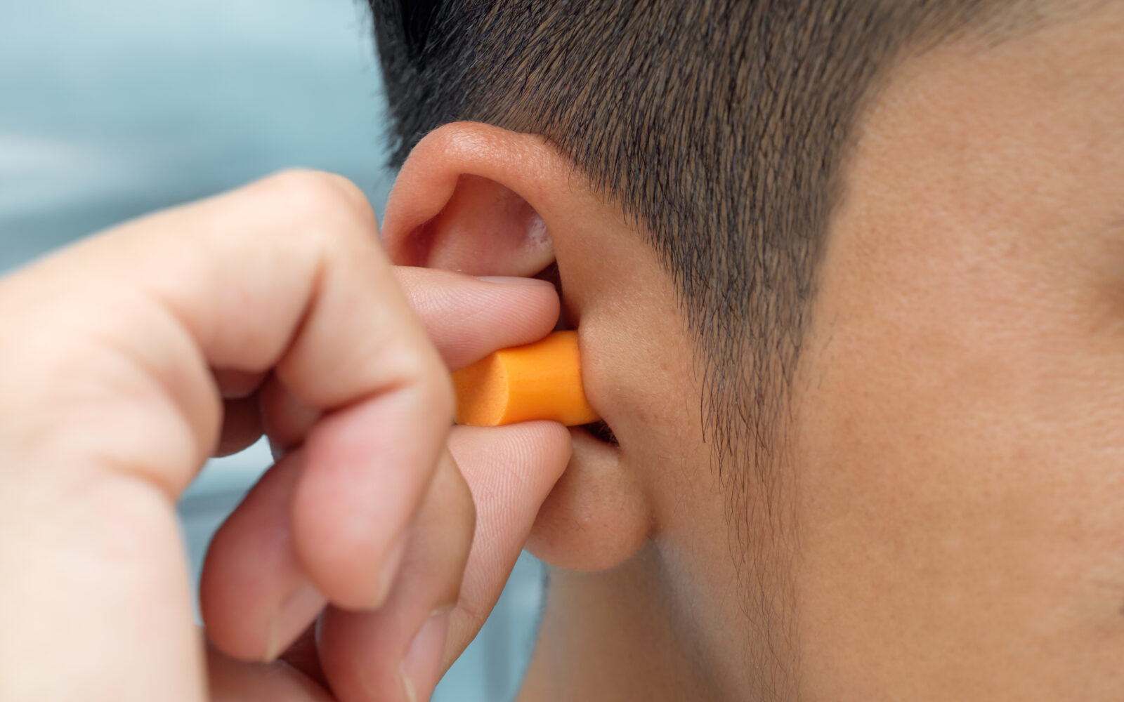 closeup of man inserting earplug into ear