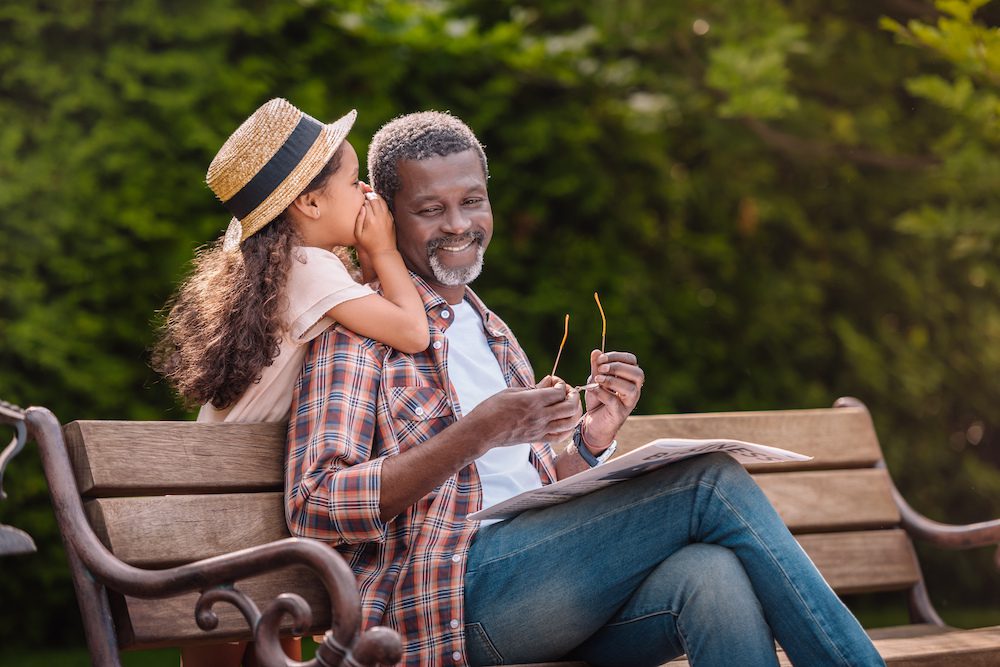 daughter whispering to father on public bench