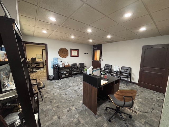 Waiting area with chairs, a water cooler, and a reception desk in a hearing center office.