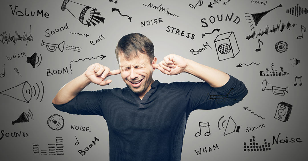 Man holding his ears with noises around him. Hearing Loss