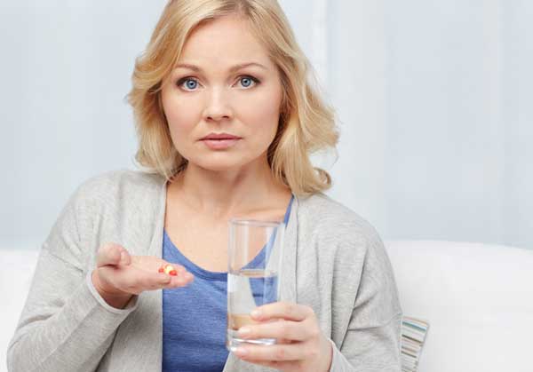 A woman troubled by hearing loss taking hormone replacement therapy pills to help with menopause.