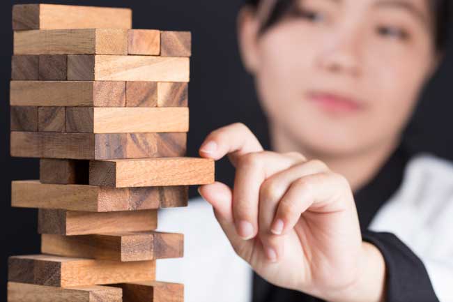 Woman pulling a Jenga block out as a metaphor for how ignoring mild hearing loss can become a larger issue.