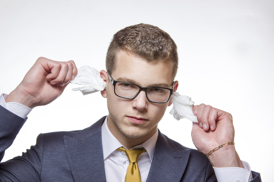 Man cleaning earwax from his ears by pulling tissues out of ear