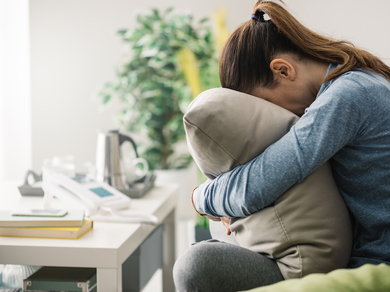 Woman with tinnitus trying to muffle the ringing in her ears with a pillow to overcome challenge.