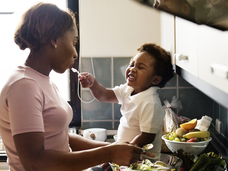 Grandma and grandson are cooking healthy food together in the kitchen to prevent hearing loss.