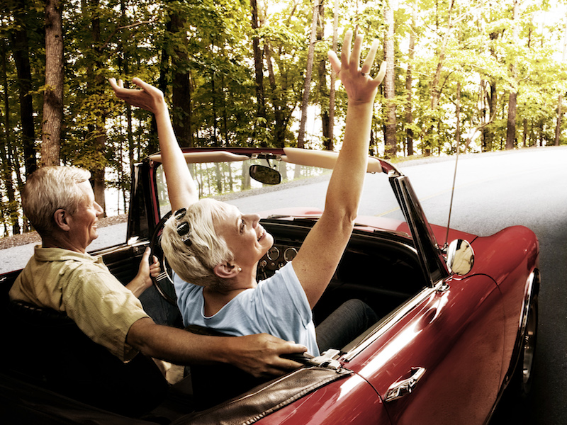 Woman with hearing loss happy to have her freedom and independence while riding in a convertible.