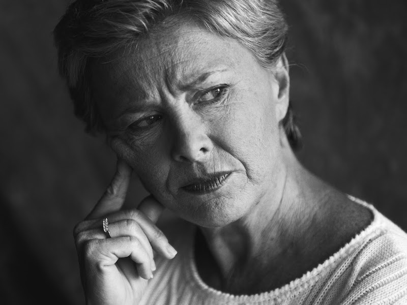 Woman suffering from feedback in her hearing aids covering her ears.