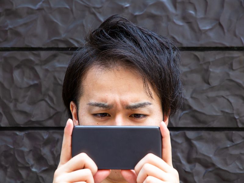 Man looking up information on tinnitus in social media on his cell phone.