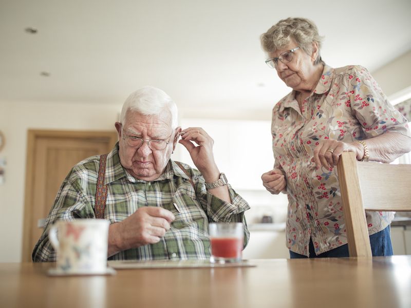 Man and his wife using tips to fix his hearing aids.