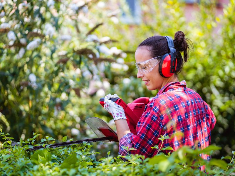 Woman protects her hearing with ear muffs while doing yardwork.