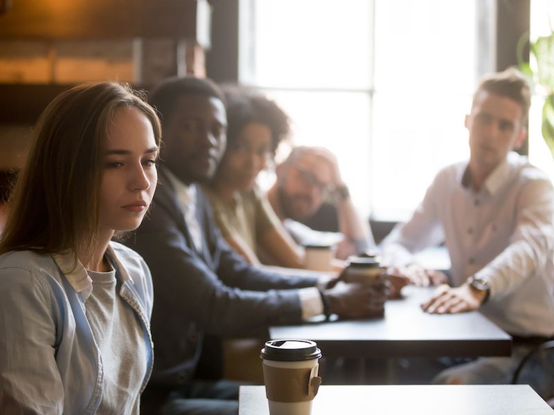 Young woman suffering from hearing loss does not hear her friends.