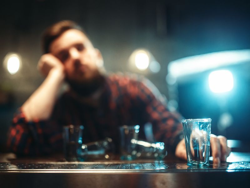 Young man with hearing loss drinking more alcohol than he should.