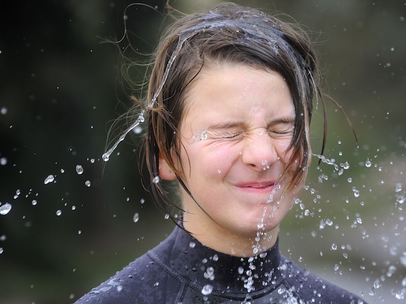 Woman trying to clear a clogged ear by shaking water out of it.