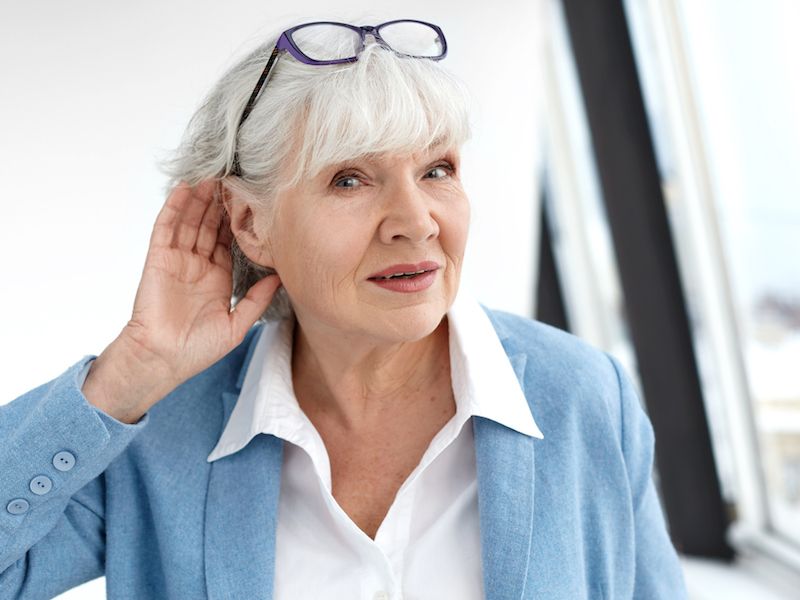 Woman holding ear because her hearing aid isn't working.