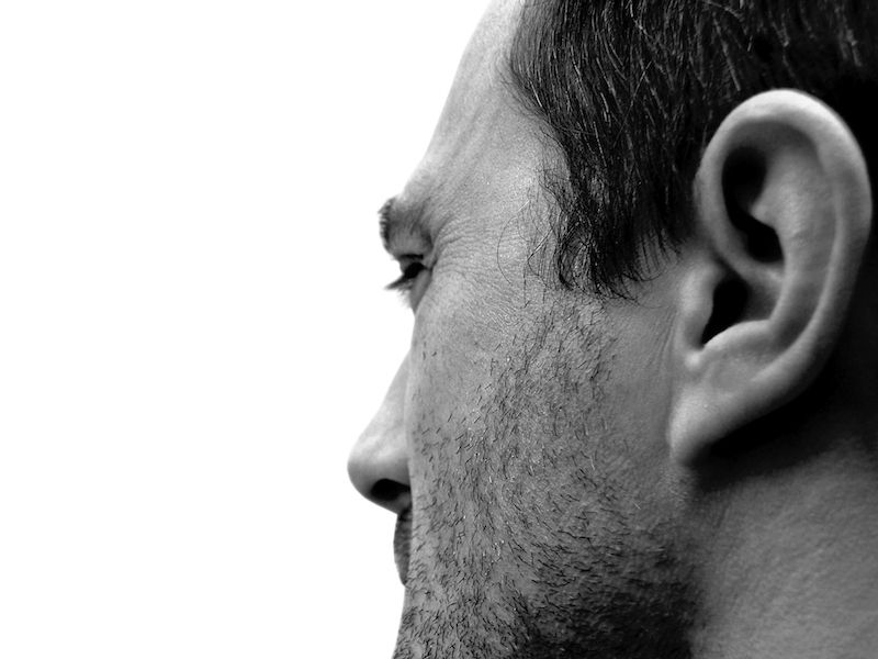 Man grimacing from ringing in his ear.