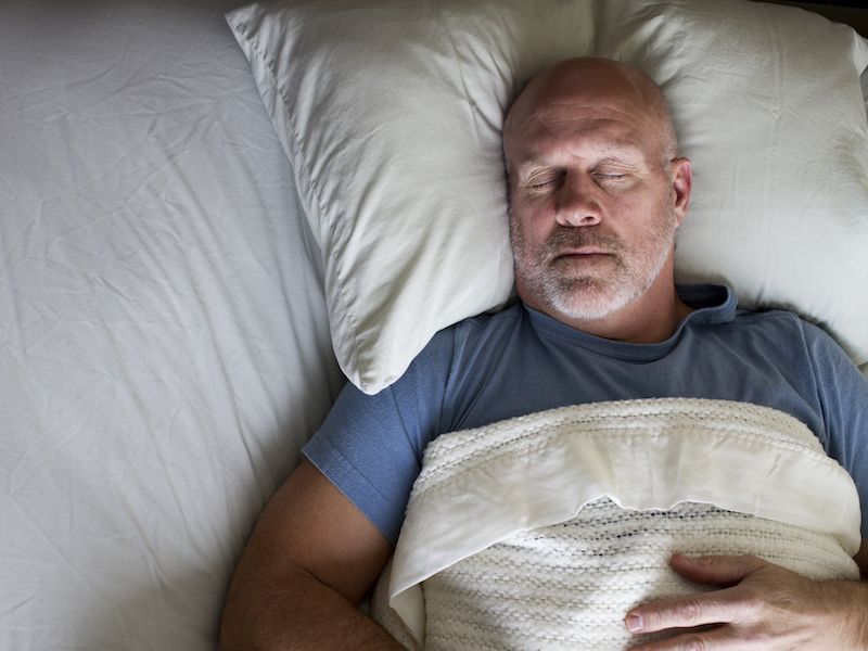 Man with hearing loss sleeping better because he has hearing aids.