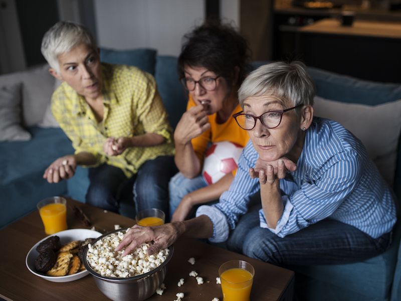 Woman can't hear the television while watching with friends.