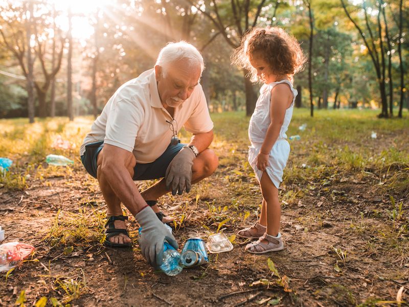 Man and young child recycling in a forest discuss how to recycle hearing aids.