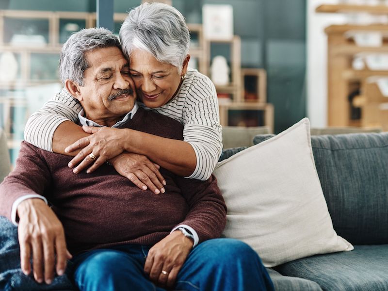 Primary caretaker of a senior hugging him after making a hearing test appointment.