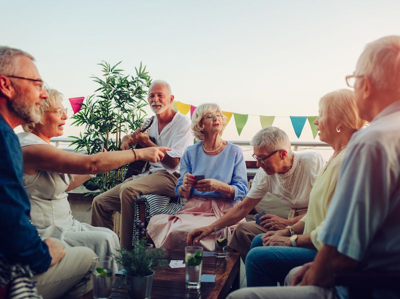 Mature adults with hearing aids playing cards instead of being isolated.