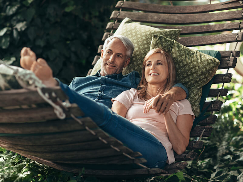 Man who got rid of tinnitus using a hearing aid on a hammock with his wife.