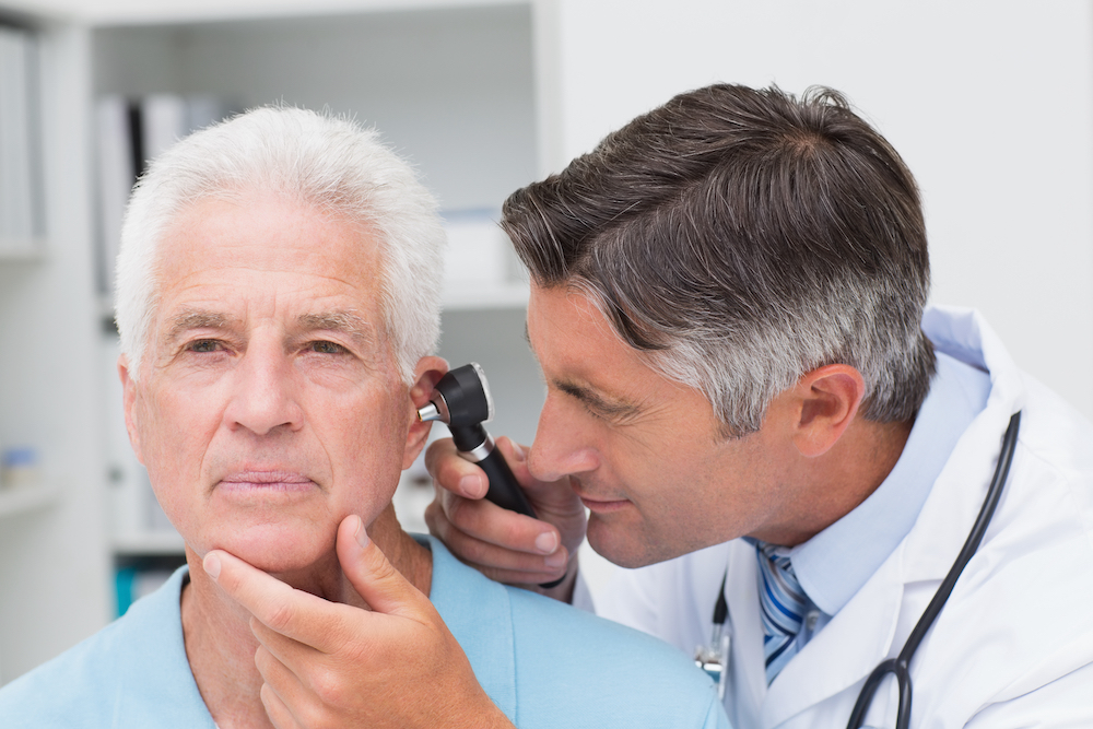 man having his ear canal inspected by hearing specialist