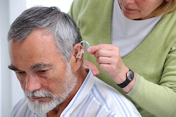 elderly man being fitted with new hearing aid devices
