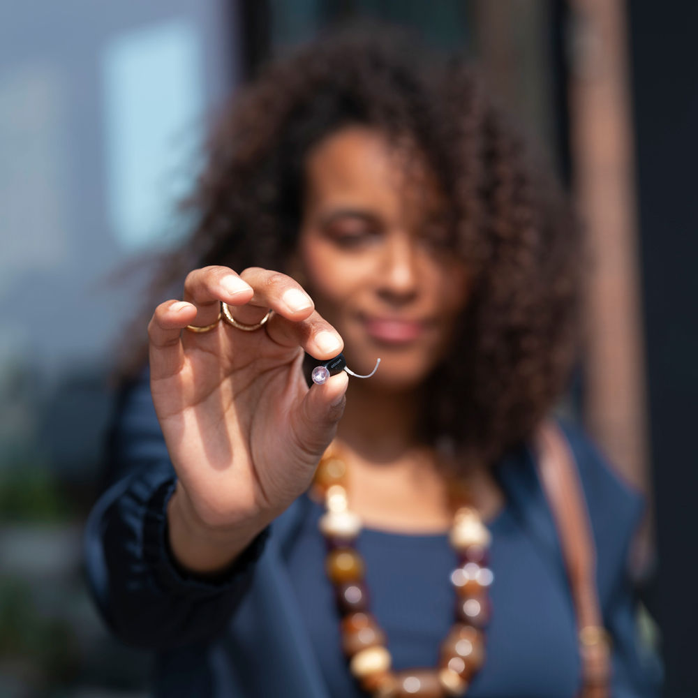 oticon zeal lifestyle square woman holding hearing aid in hand