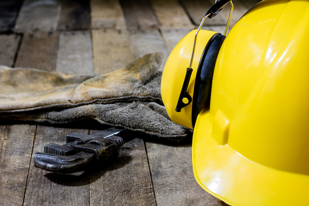 yellow ear protectors next to hard hat and wrench