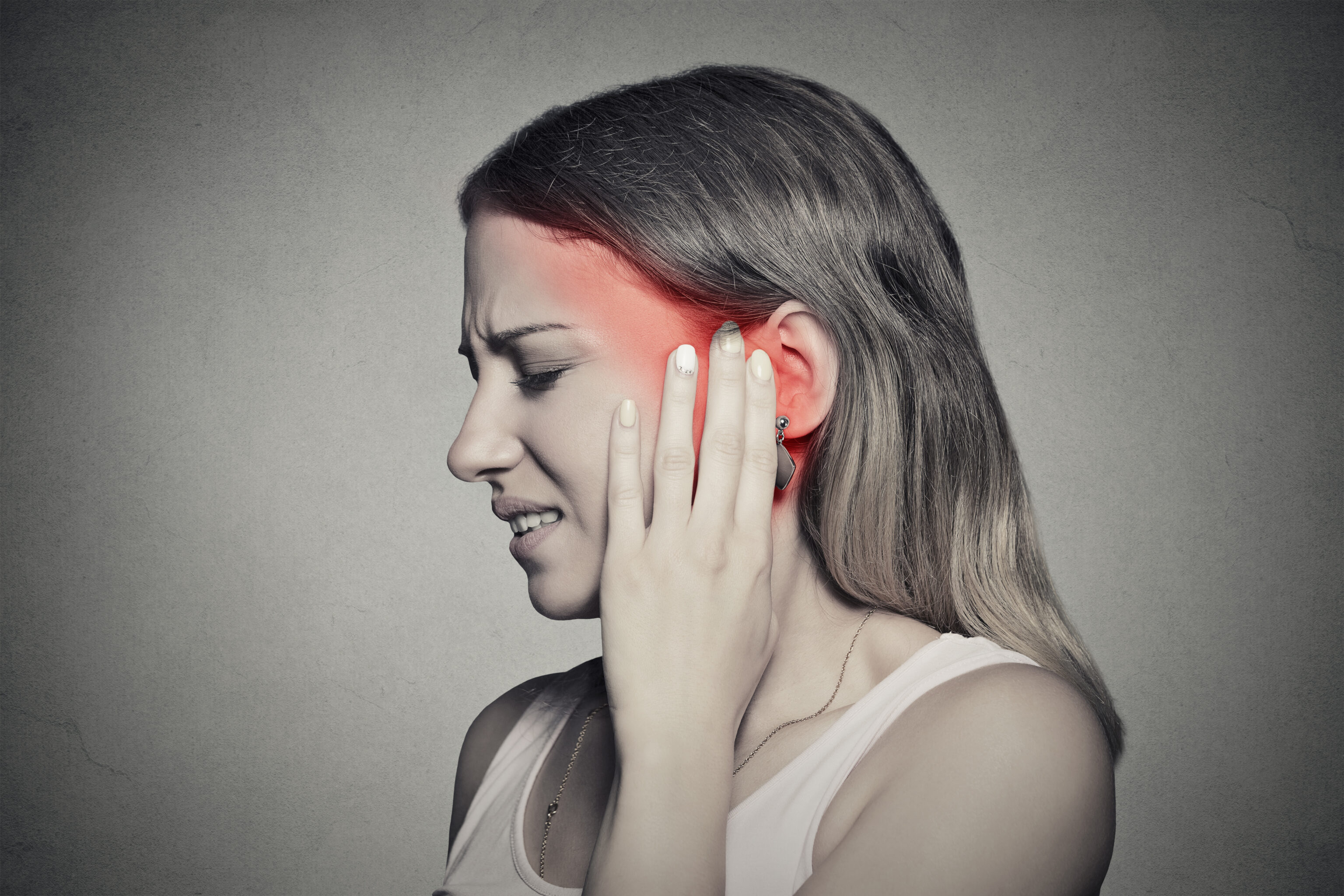 woman with ringing in ears against gray background