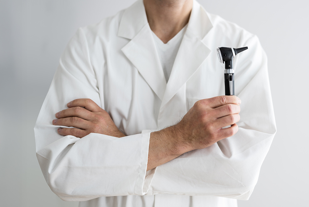male provider in coat holding otoscope