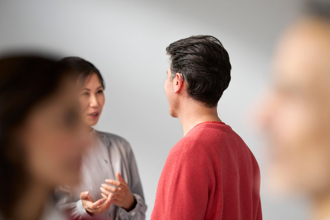 resound sensia lifestyle man wearing rie silver hearing aid talking to woman long