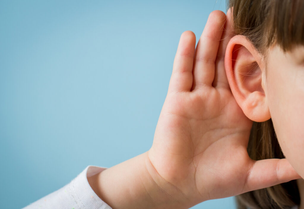 Little girl with hearing problem on light blue background Close