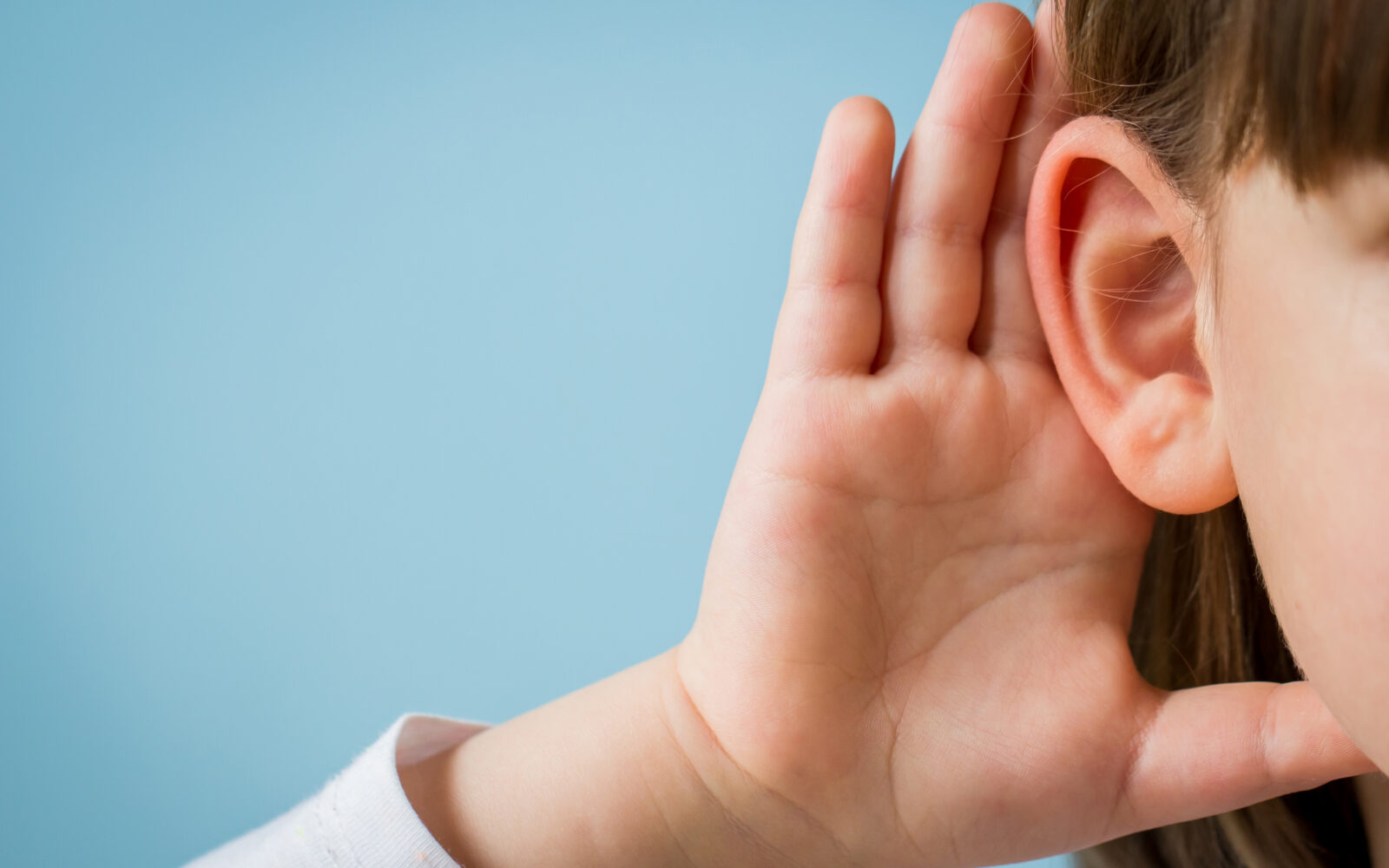 Little girl with hearing problem on light blue background Close
