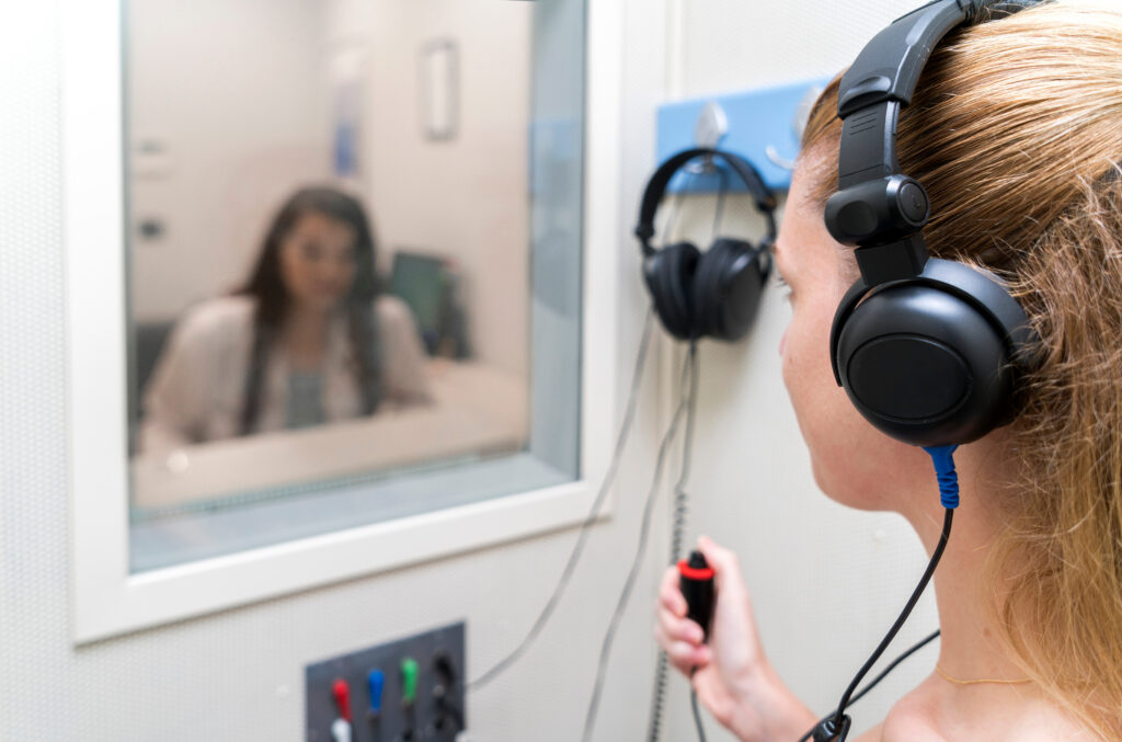 Audiologist woman doing the hearing exam to a mixed race woman patient using an audiometer in a special audio room Audiometric testing Hearing loss treatment
