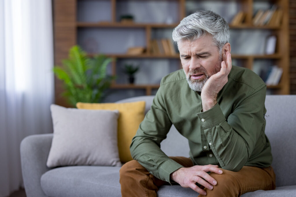 Mature man suffering from severe earache and pain at home