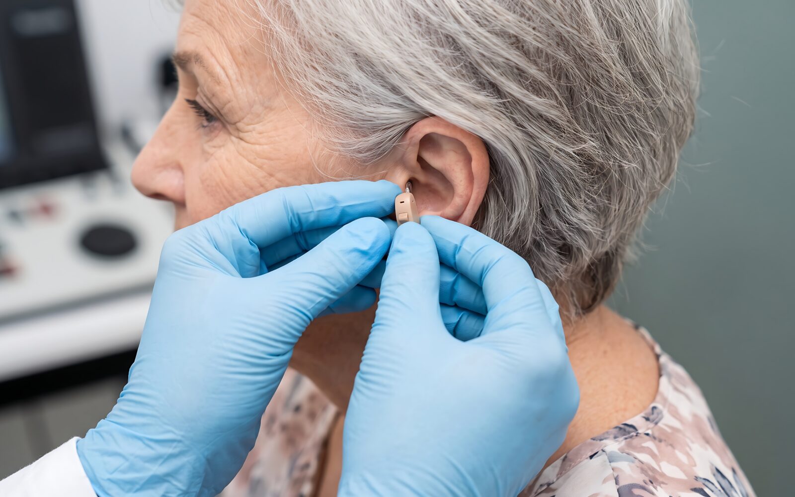 Professional audiologist fitting a modern invisible hearing aid device for an elderly woman