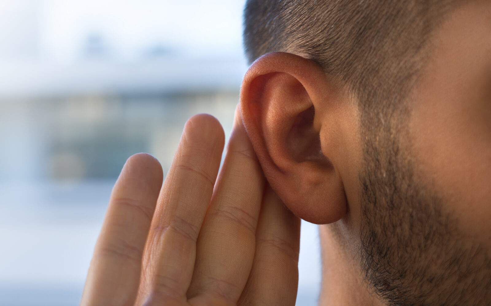 Young man with hearing problems, hearing loss or hard of hearing