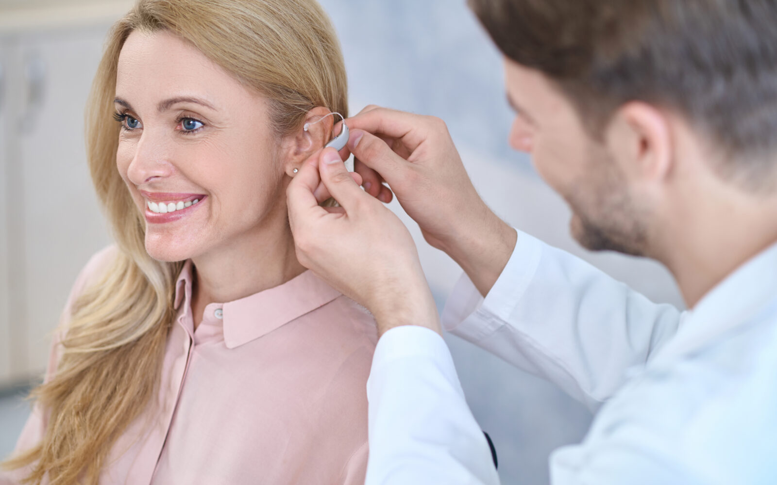Man putting hearing aid on womans ear
