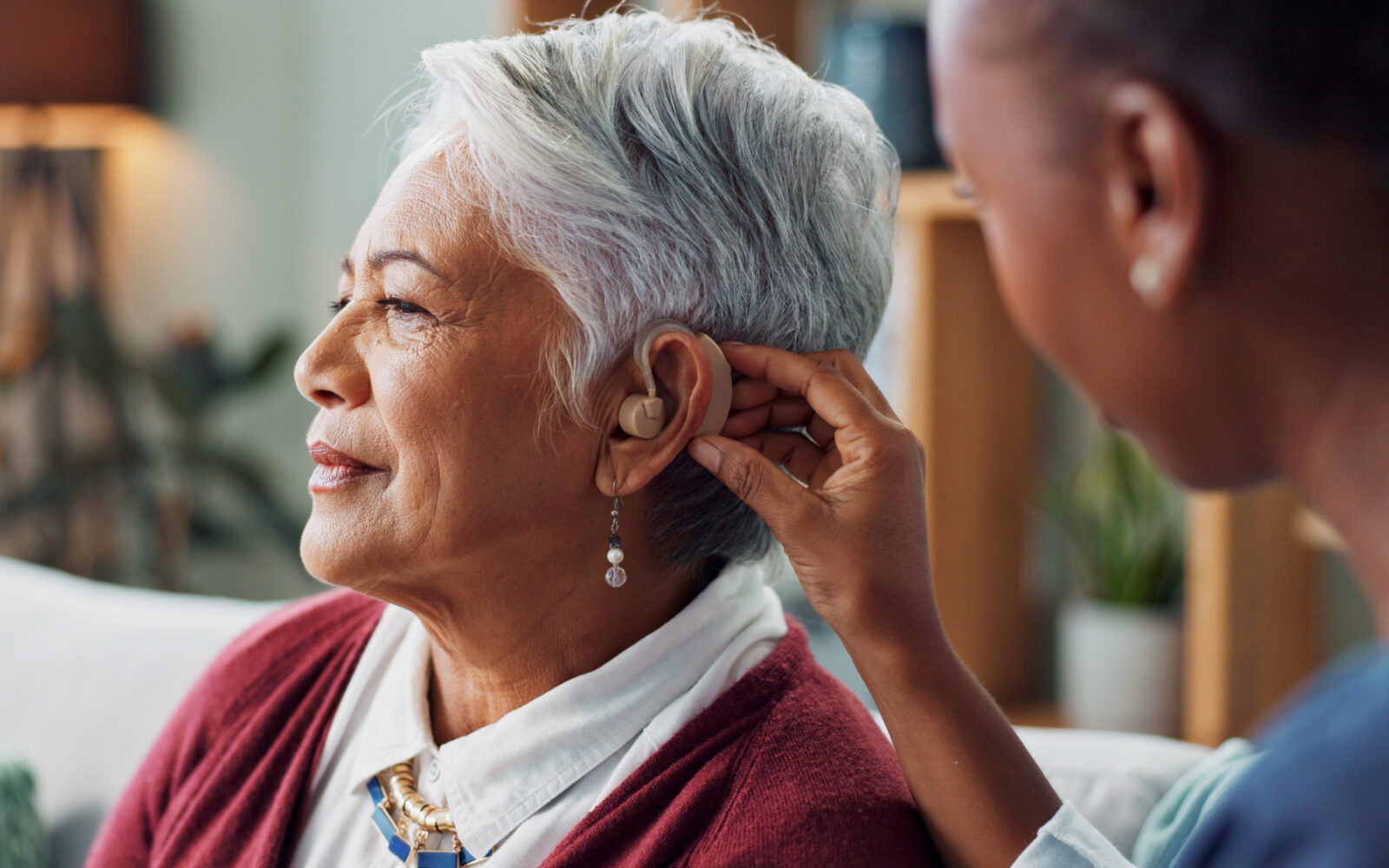 Nurse, woman and hearing aid on ear for medical support, wellness and innovation of disability People, healthcare worker and deaf patient with audiology implant, service or help for sound waves