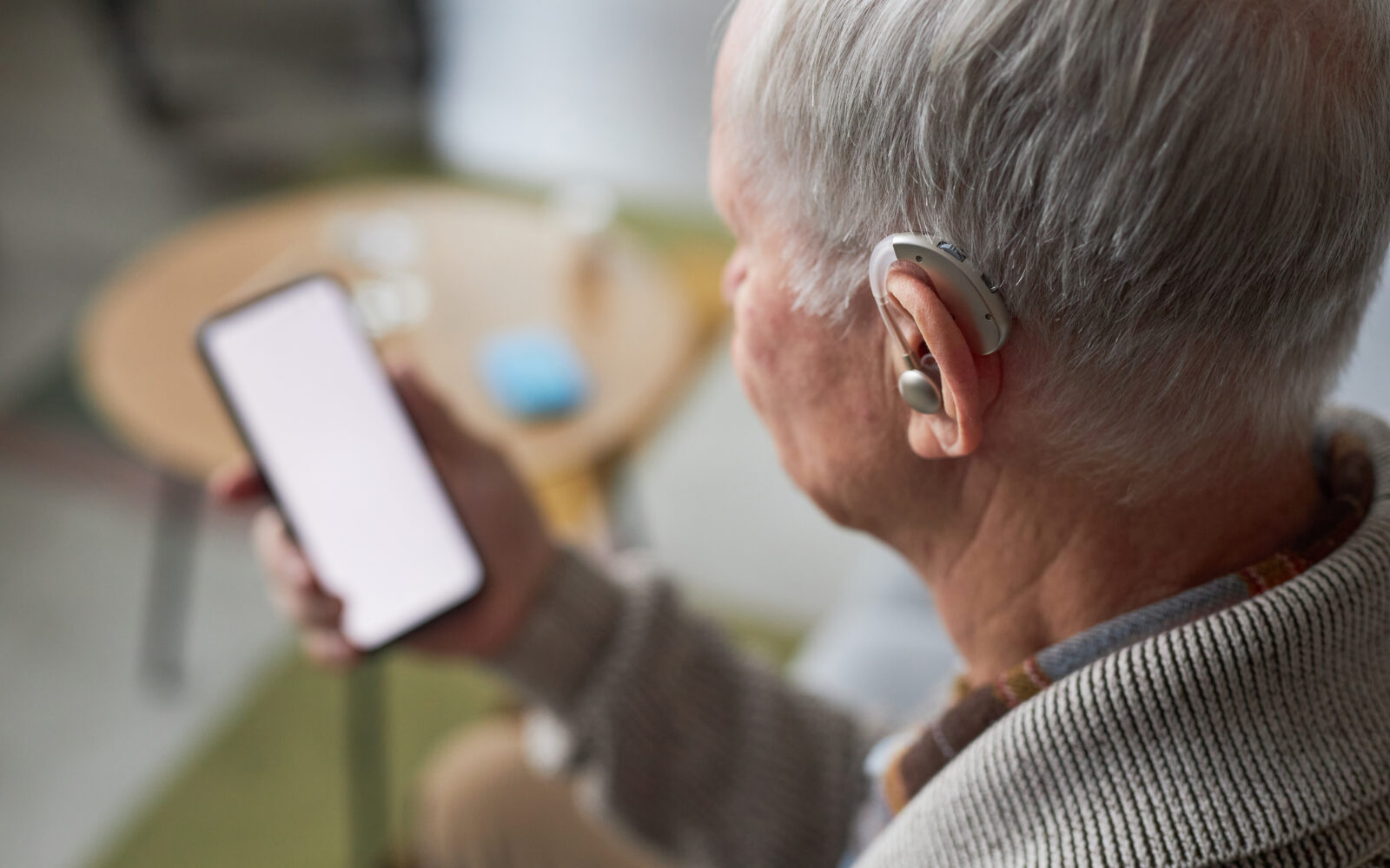 Senior man with hearing aid using smartphone