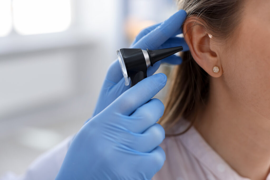 Hearing test Doctor examining woman's ear with otoscope in clinic, closeup Space for text