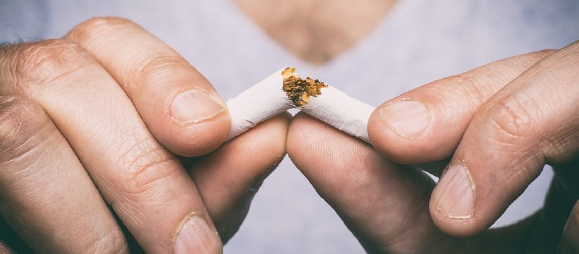 person breaking a cigarette in half
