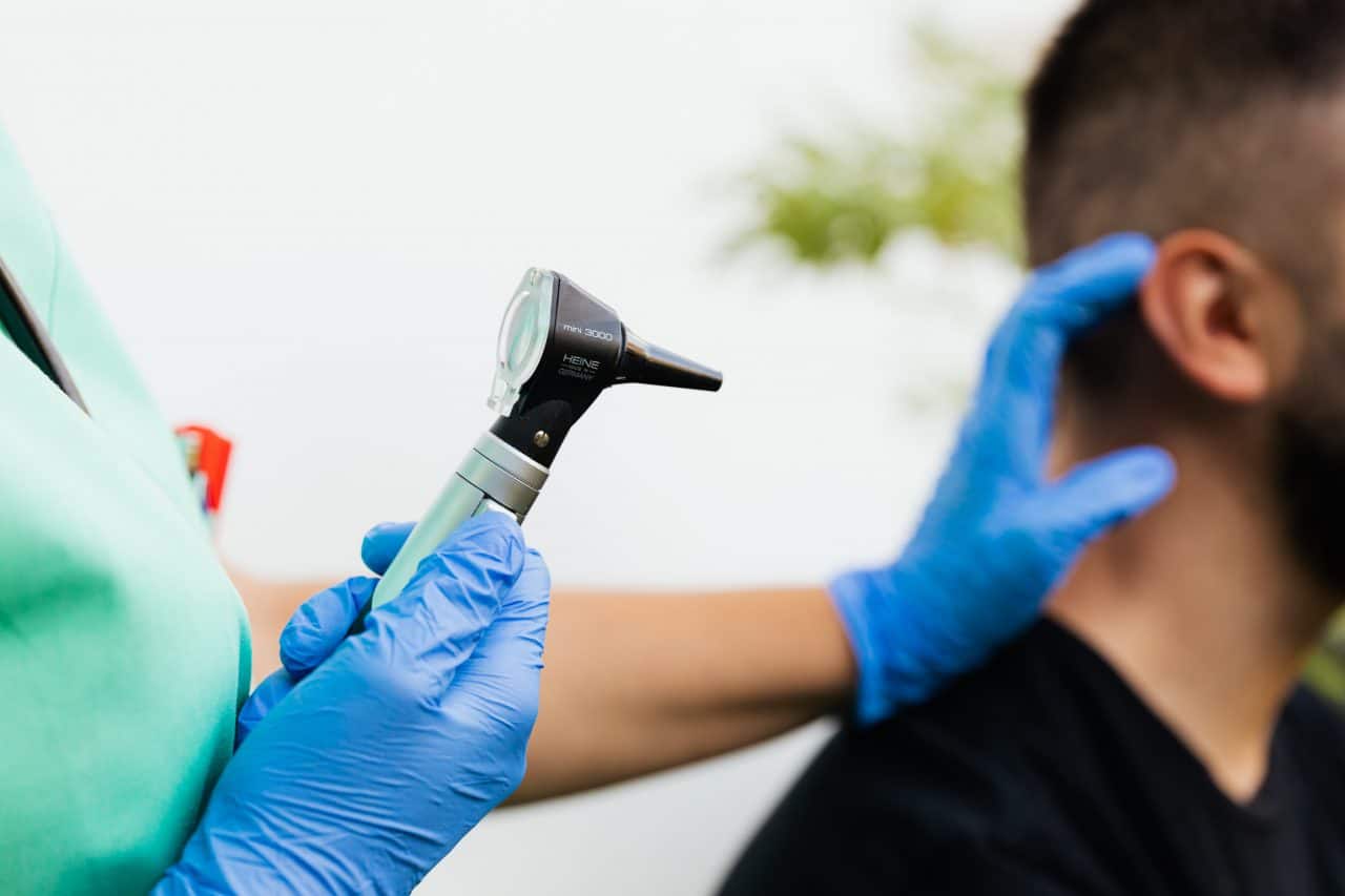 audiologist inspecting man's ear