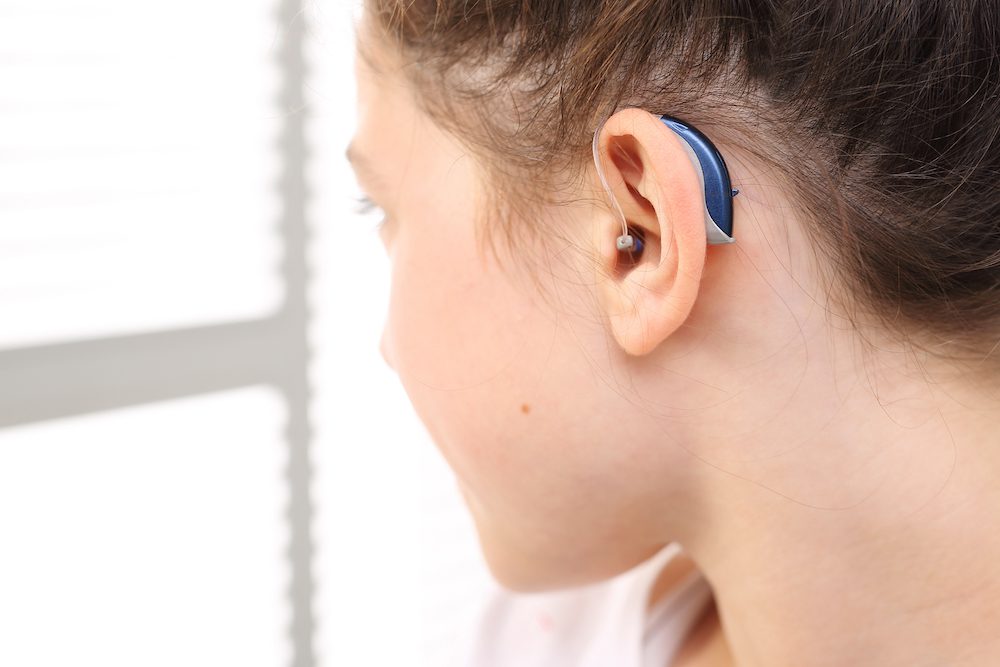 young woman showing off her new blue hearing aids