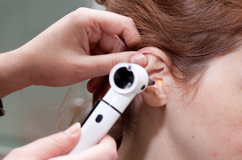 hearing specialist examining patient's ear